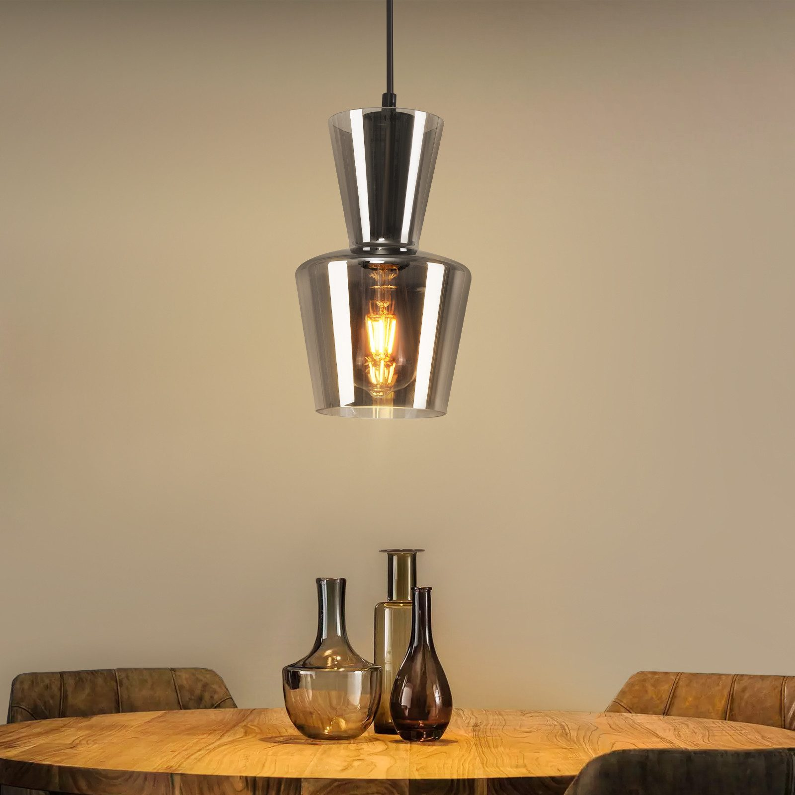 Lampa wisząca wisi nad stołem z wazonami. Ciepła żarówka znajduje się w szklanym kloszu.