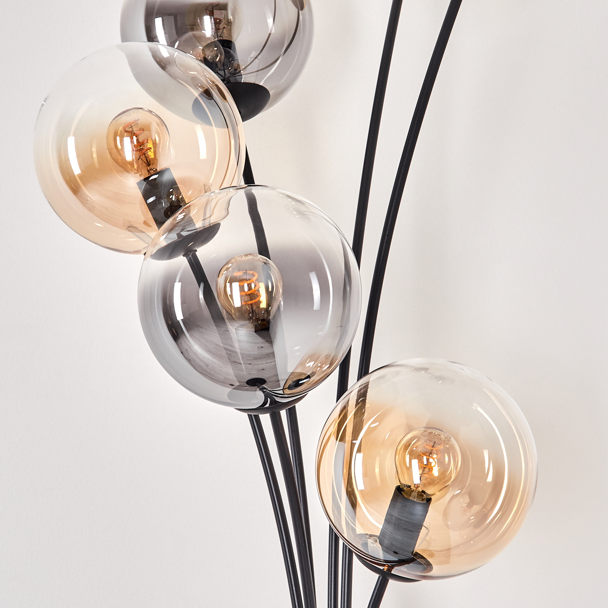 Nahaufnahme einer schwarzen Stehlampe mit fünf Glaskugeln, einige bernsteinfarben und einige grau.