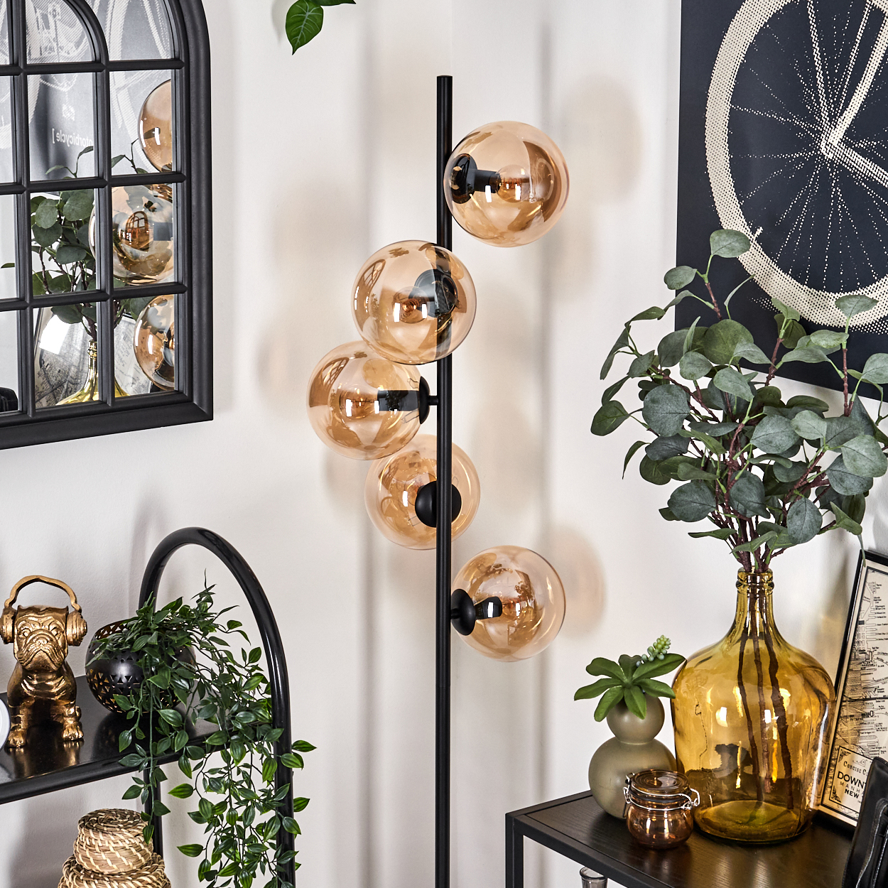 Ein modernes Wohnzimmer mit einer Stehlampe mit bernsteinfarbenen Glühbirnen und Dekorationsartikeln auf Regalen und Tischen.