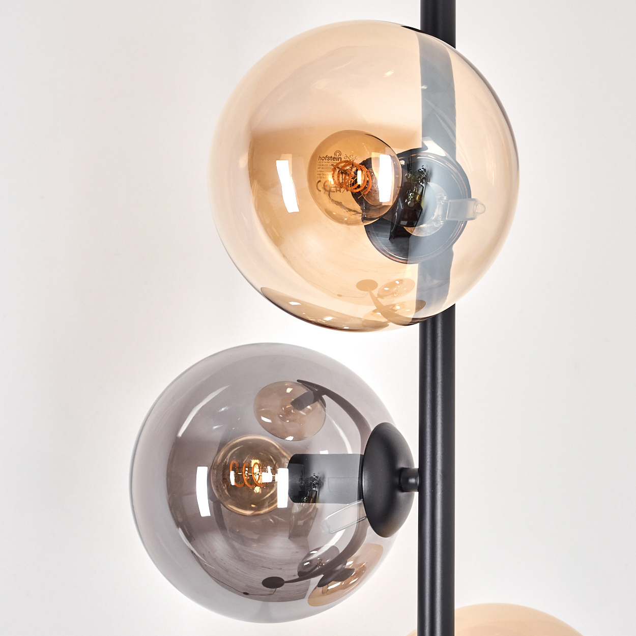 Nahaufnahme einer Stehlampe mit zwei Kugelschirmen; einer bernsteinfarben und einer verspiegelt.