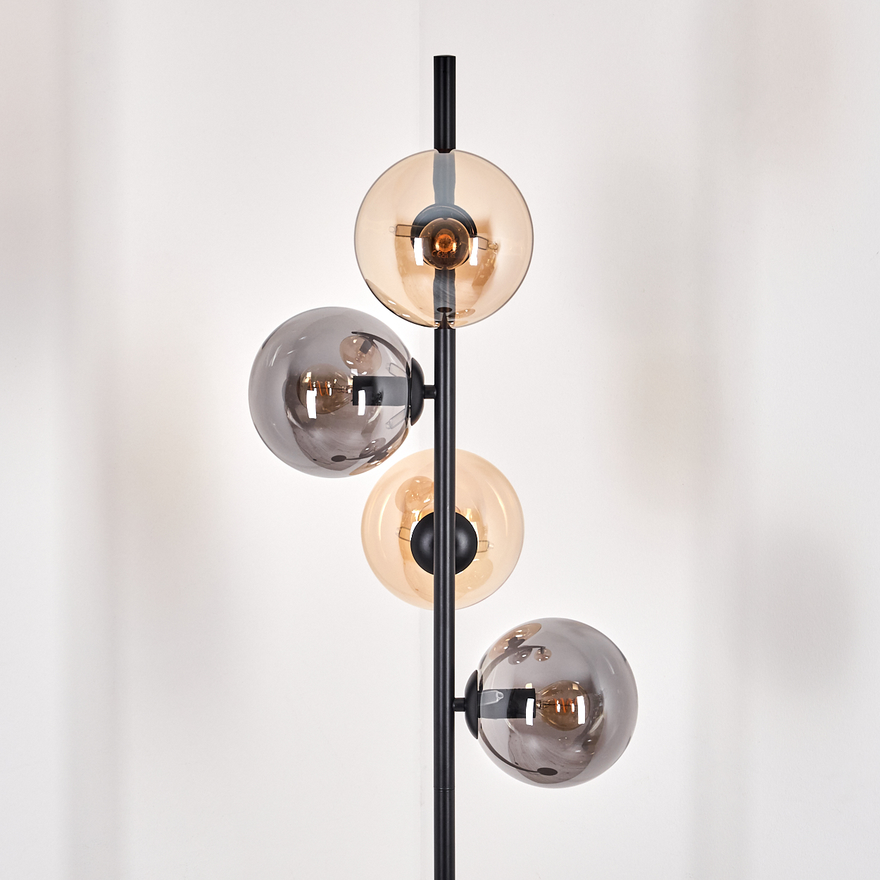 Stehlampe mit vier Kugelschirmen, schwarzem Rahmen und weißem Hintergrund.