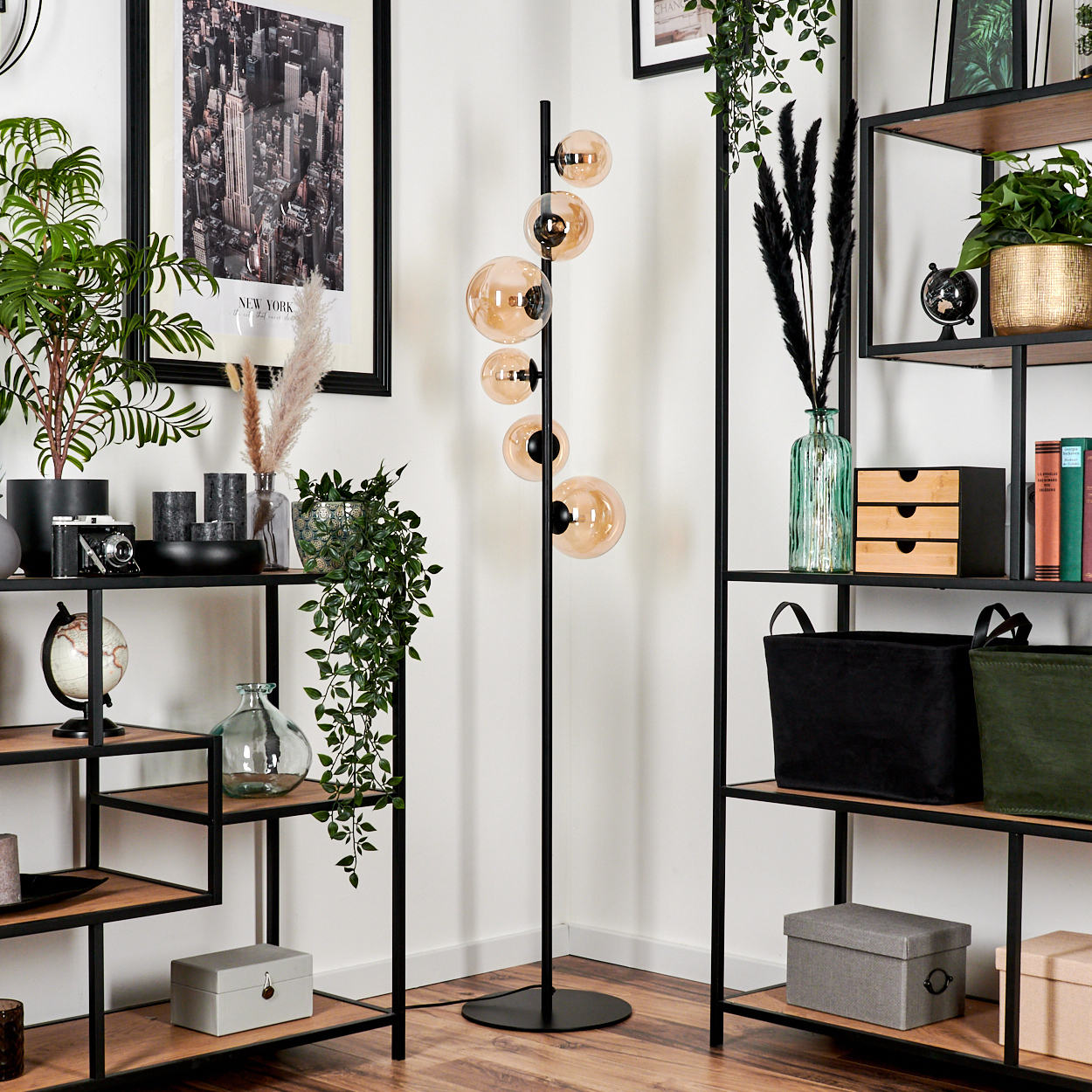Zimmer mit Stehlampe mit bernsteinfarbenen Kugeln. Regale, Pflanzen und Dekorationen. New York Bild.