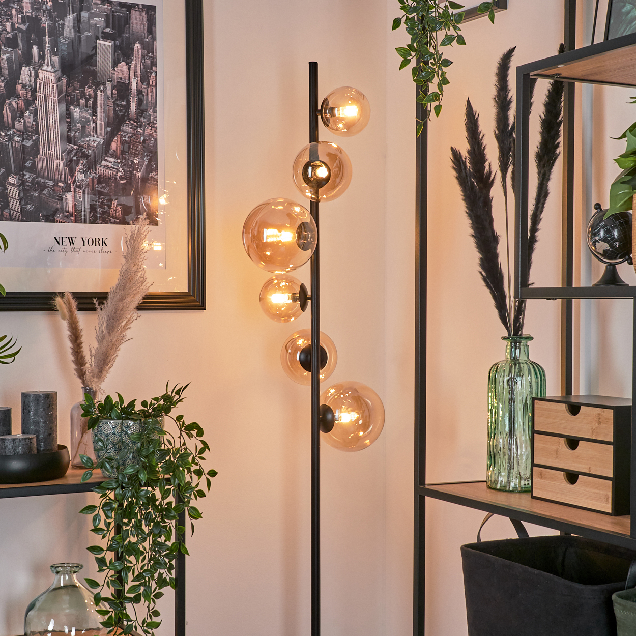 Stehlampe mit bernsteinfarbenen Glaskugelschirmen. Die Lampe steht in einem Raum mit Dekoration.