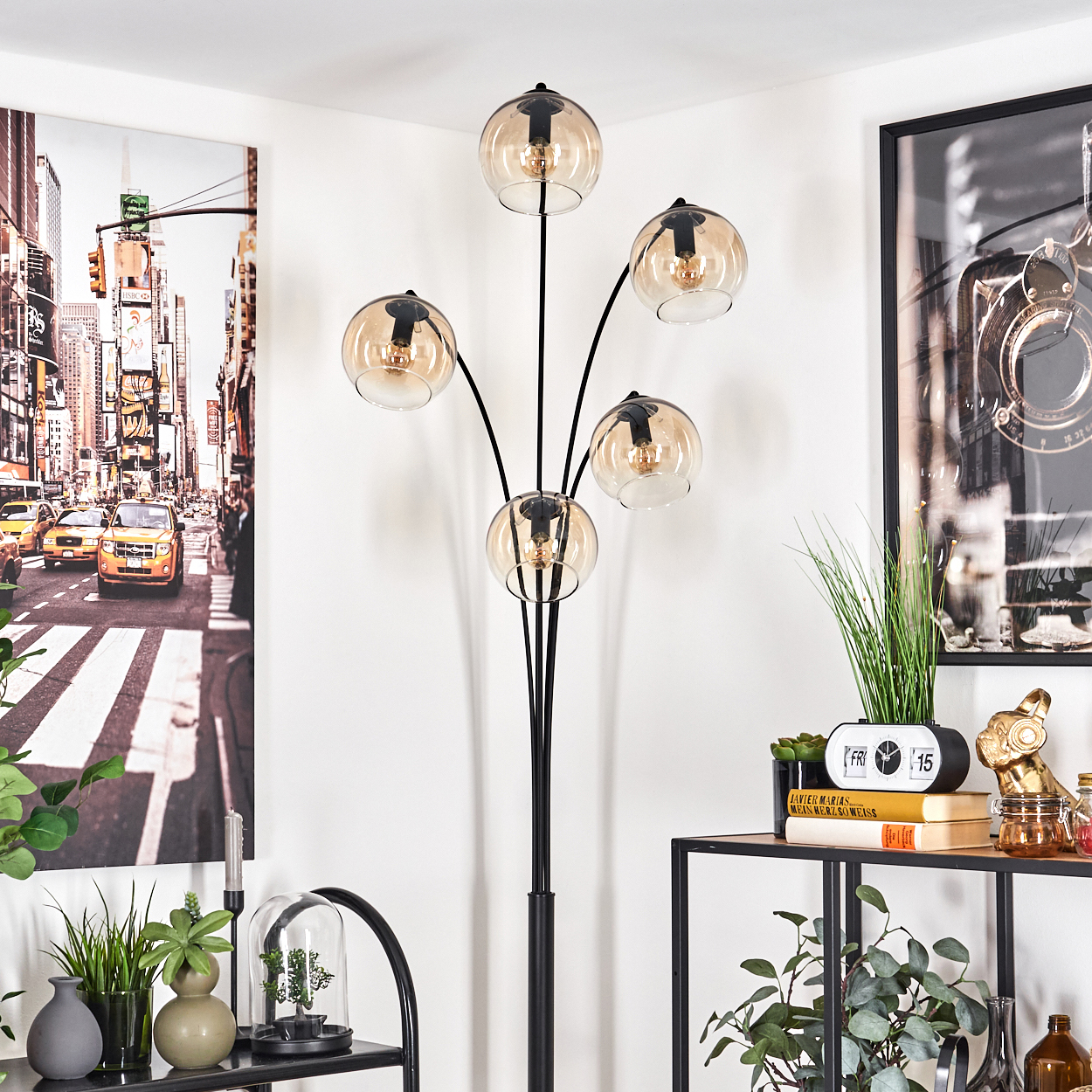 Eine schwarze Stehlampe mit fünf Kugelschirmen aus bernsteinfarbenem Glas in einem Raum.