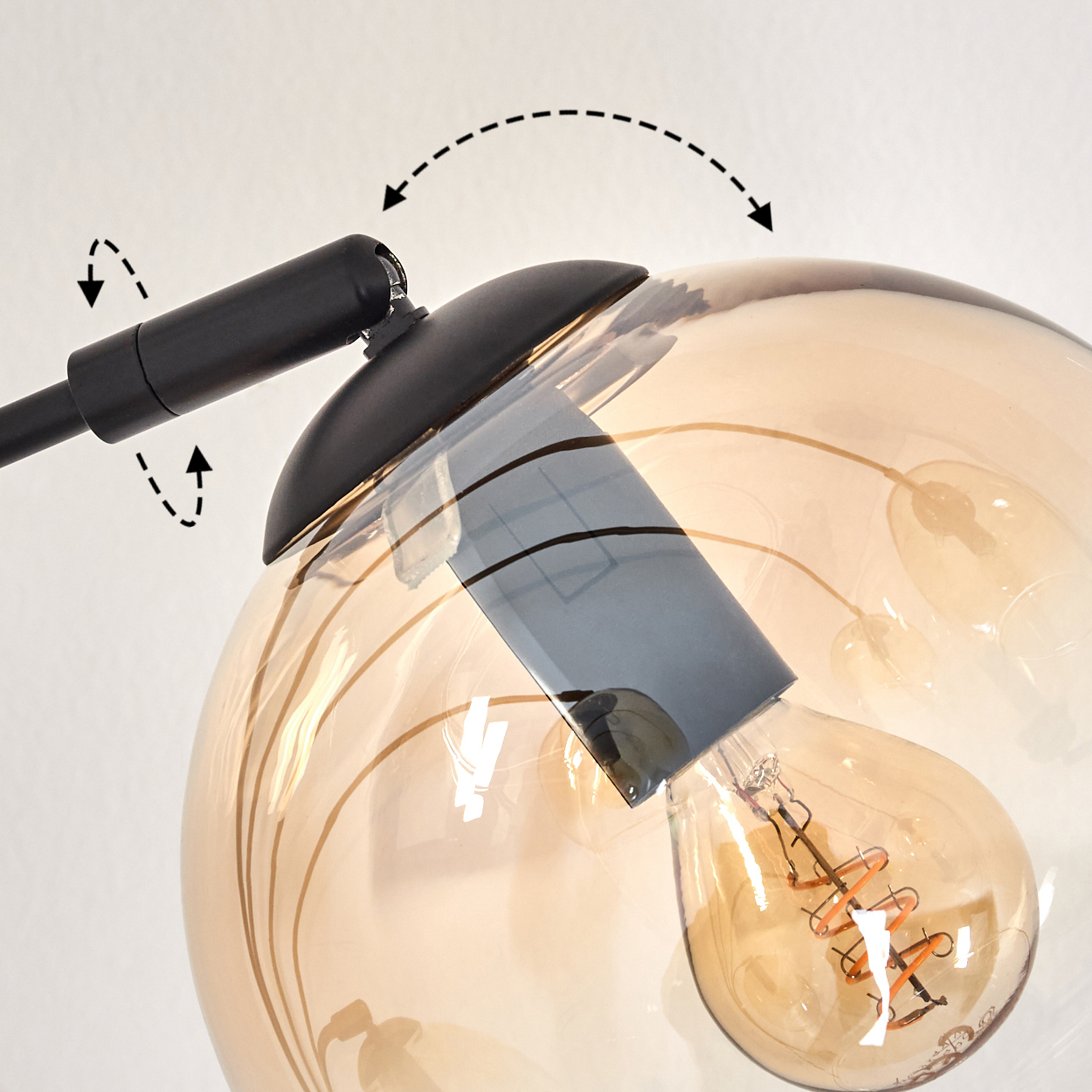 Nahaufnahme des bernsteinfarbenen Glaskugel-Schirms einer Lampe, mit Glühbirne und Halterung.