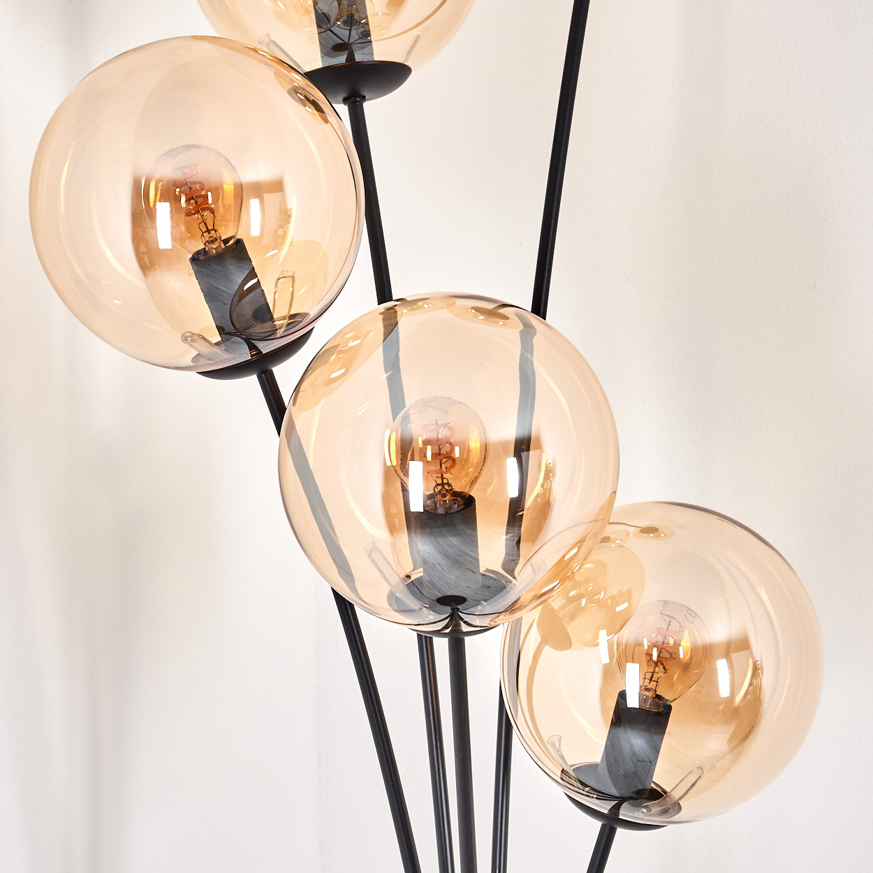 Nahaufnahme der bernsteinfarbenen Glaskugeln auf einer schwarzen Stehlampe.