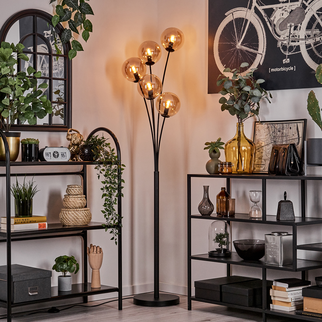 Wohnzimmer mit schwarzen Regalen, einer schwarzen Stehlampe und Pflanzen.