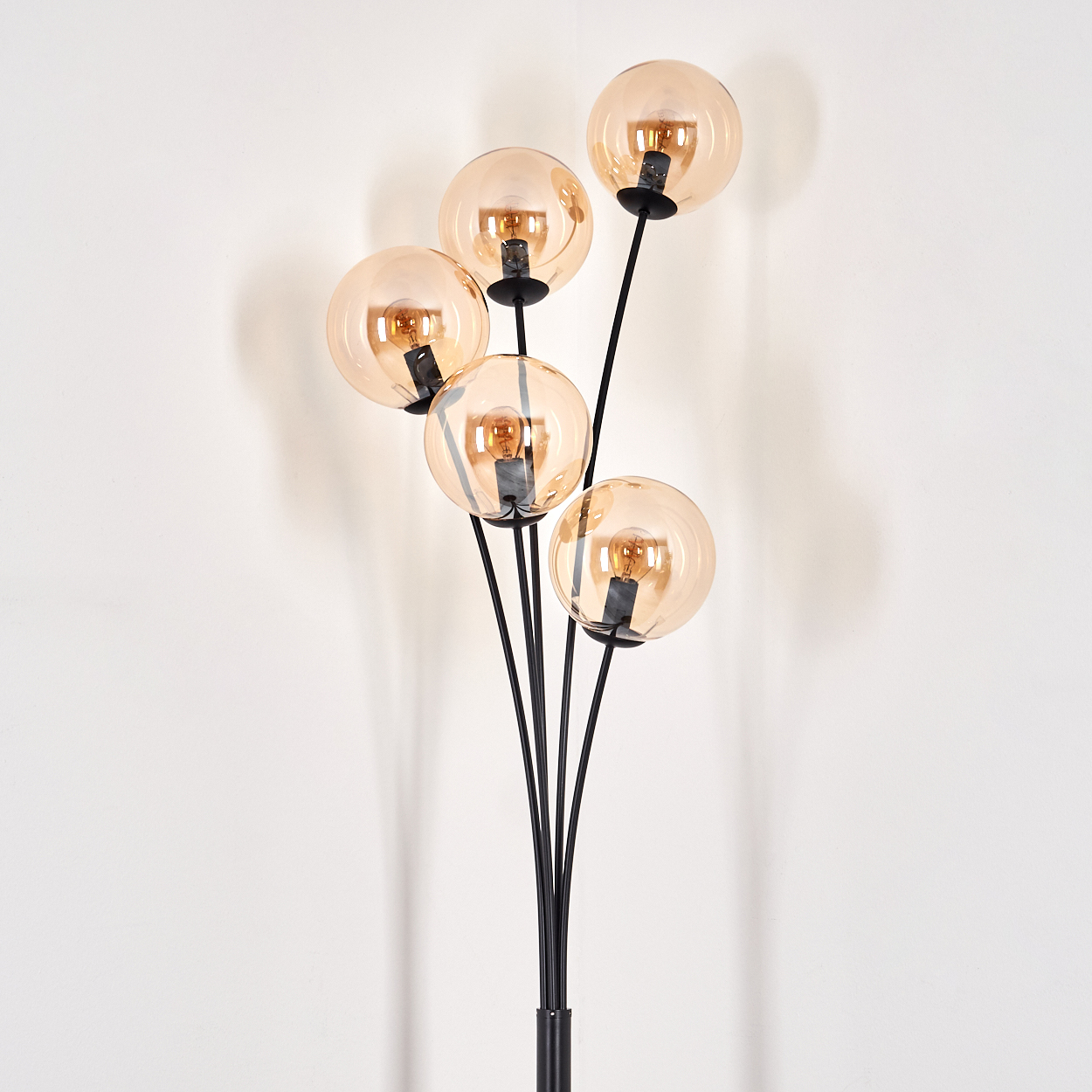 Stehlampe mit bernsteinfarbenen Glaskugeln, schwarzem Stiel und sichtbaren Glühbirnen.
