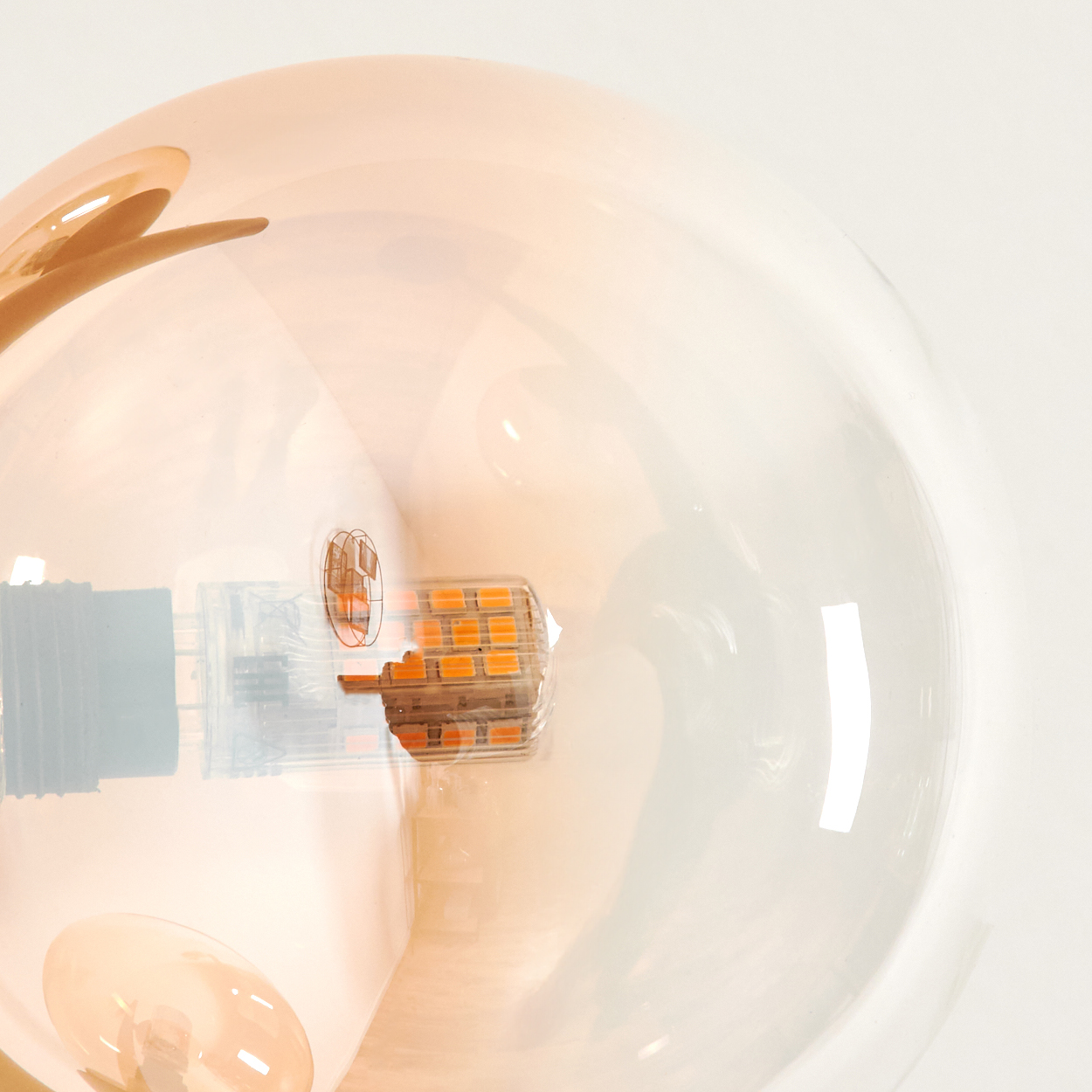 Nahaufnahme einer bernsteinfarbenen Glaskugel mit einer modernen LED-Leuchte.