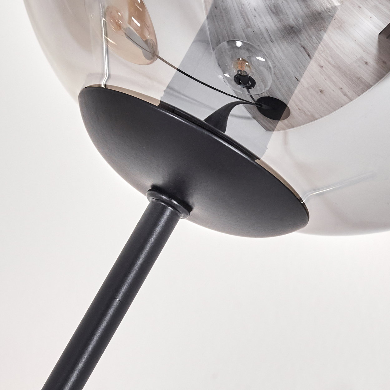 Nahaufnahme einer schwarzen Stehlampe. Die Lampe hat einen schwarzen Pfosten mit einer Glaskugel.
