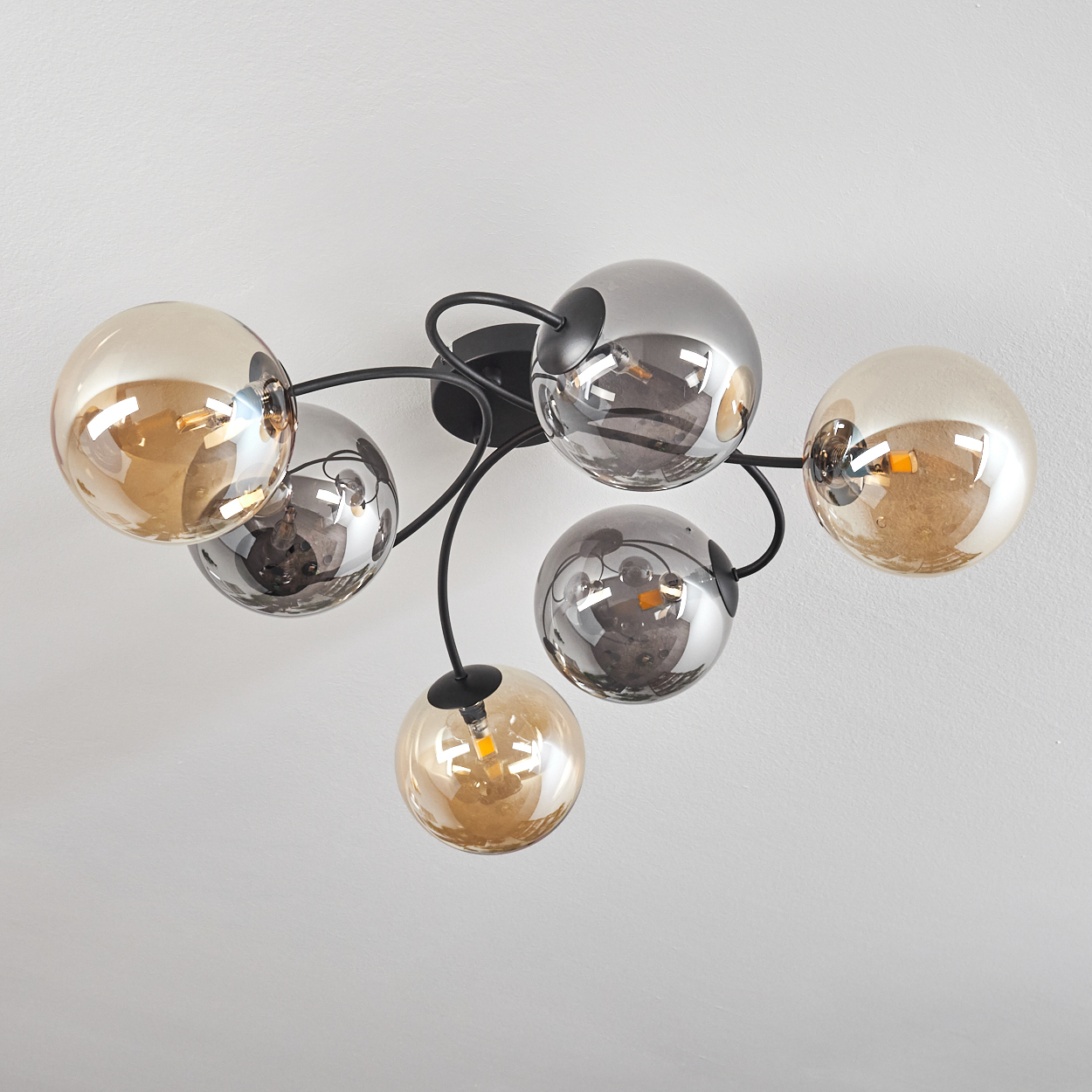 Deckenlampe mit sechs bernsteinfarbenen und klaren Glaskugeln. Hintergrund: weiße Decke.