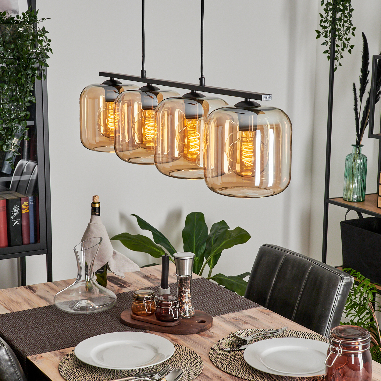 Vier Pendelleuchten mit bernsteinfarbenem Glas über einem Holztisch. Esszimmer mit Dekoration.