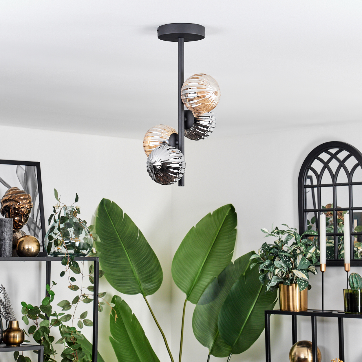 Eine Deckenlampe mit vier gerippten Glaskugeln in Bernstein und Silber, mit Dekoration im Hintergrund.
