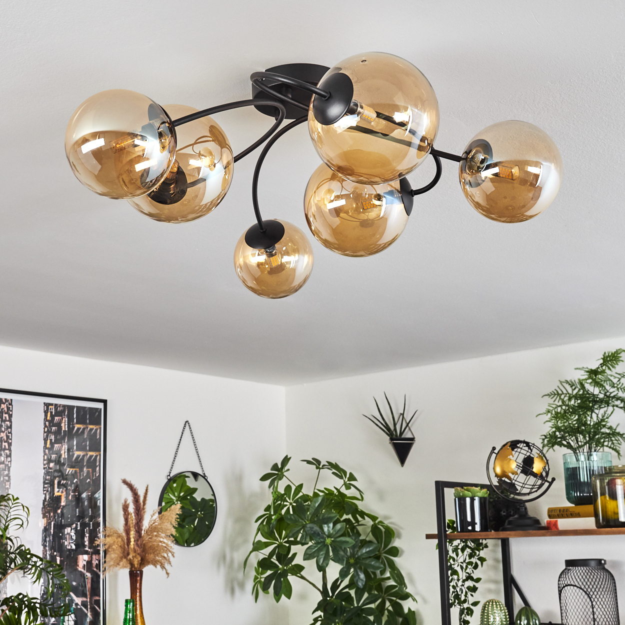 Deckenlampe mit sechs bernsteinfarbenen Glaskugeln. Pflanzen, Spiegel und Deko im Hintergrund.