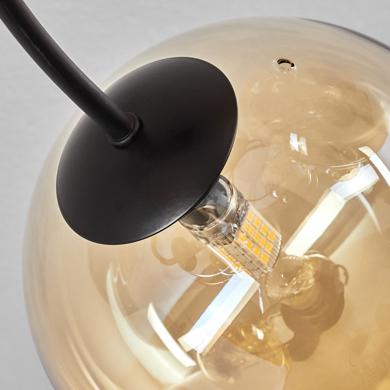 Nahaufnahme einer bernsteinfarbenen Glühbirne, schwarze Halterung. Die Birne hat LED-Leuchten.
