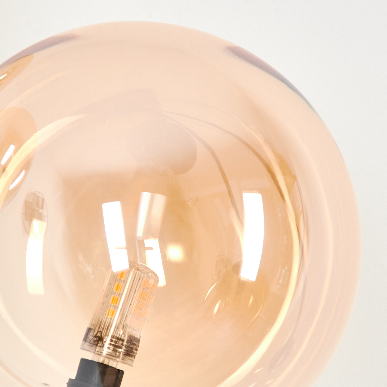Nahaufnahme einer einzelnen bernsteinfarbenen Glaskugel mit der Lichtquelle im Inneren.