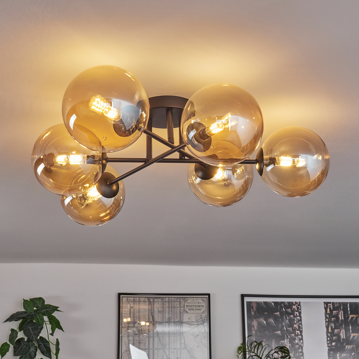 Deckenleuchte mit sechs bernsteinfarbenen Glaskugeln. Schwarze Hardware und weiße Decke.