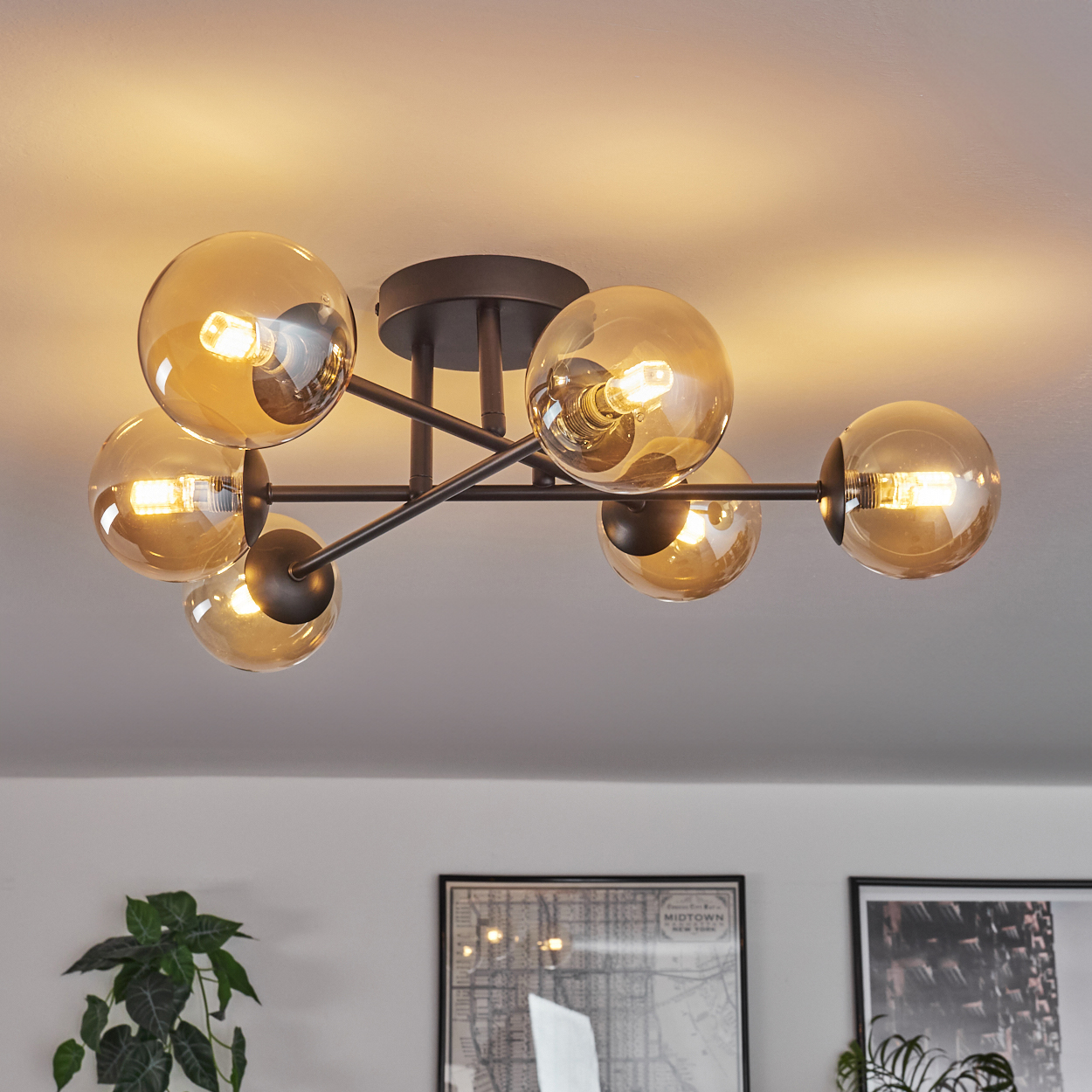 Eine Deckenlampe mit sechs bernsteinfarbenen Glasschirmen. Die Lampe ist an.