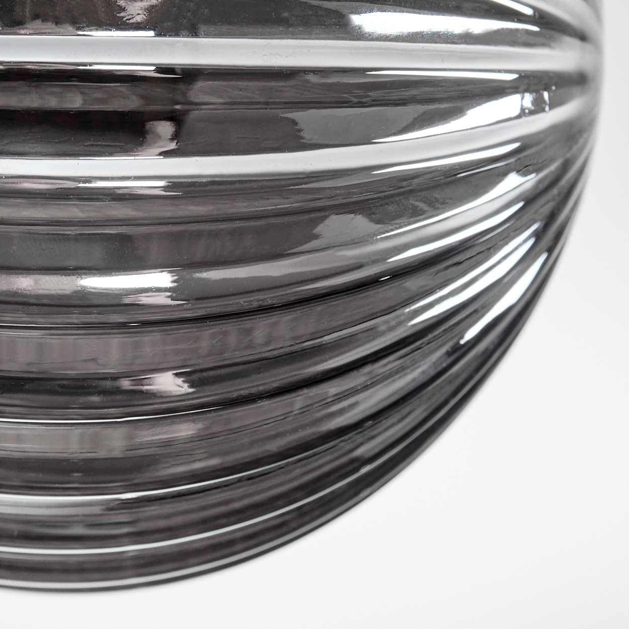Nahaufnahme eines silbernen, gerippten Glaskugels von einer Lampe, die die gekrümmte Oberfläche zeigt, die Licht reflektiert.