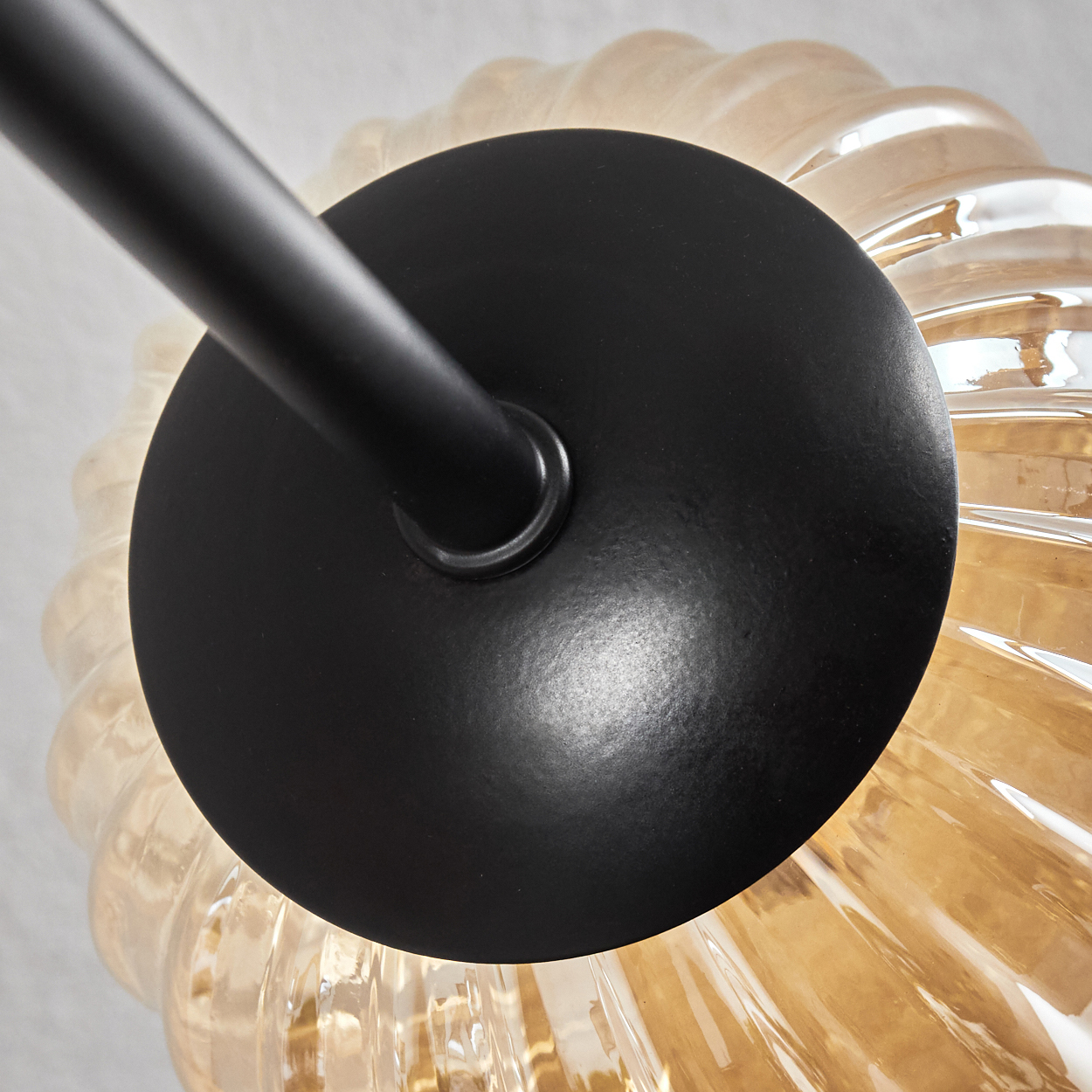 Nahaufnahme einer Glühbirne mit Spiralmuster und bernsteinfarbener Farbe, an schwarzer Halterung befestigt.