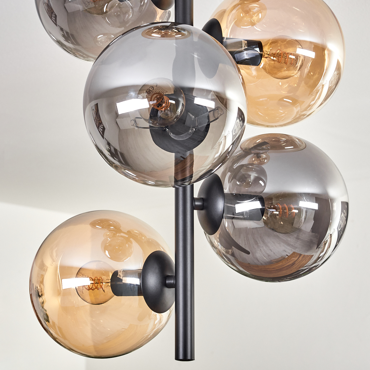 Nahaufnahme der Stehlampe. Fünf Glaskugeln mit Glühbirnen auf schwarzem Rahmen. Weißer Hintergrund.