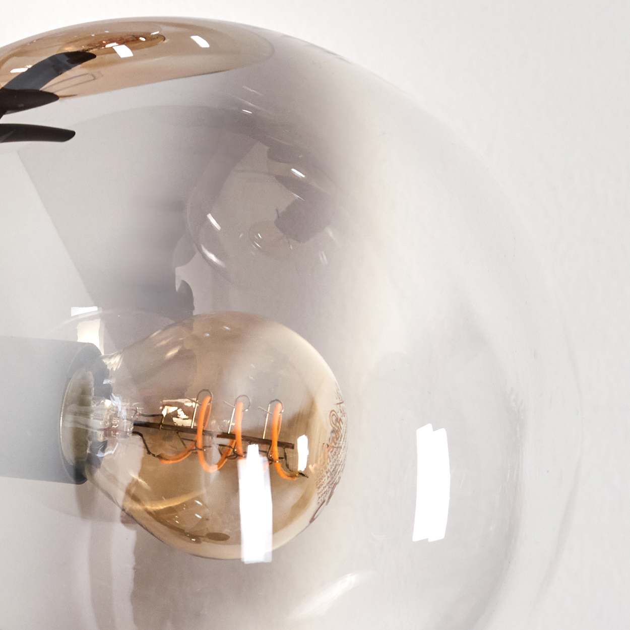 Nahaufnahme einer Glühbirne in einer bernsteinfarbenen Glaskugel einer Stehlampe.
