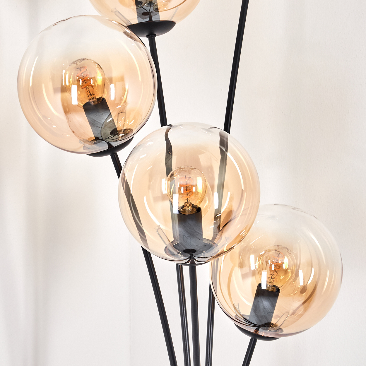 Stehlampe mit bernsteinfarbenen Glaskugeln und sichtbaren Glühbirnen, vor weißem Hintergrund.