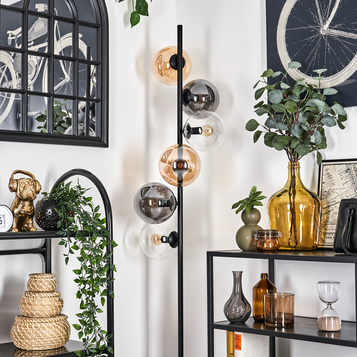 Eine Zimmerecke mit Stehlampe, Regalen und Dekoration.
