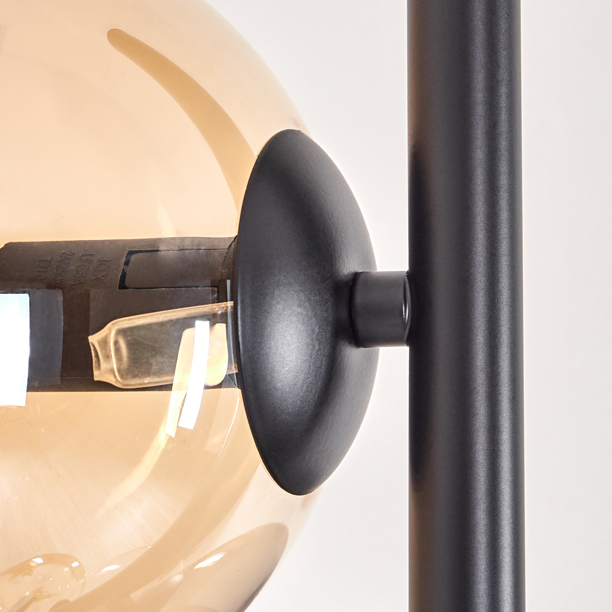 Nahaufnahme einer schwarzen Lampe und einer orangefarbenen Glaskugel.
