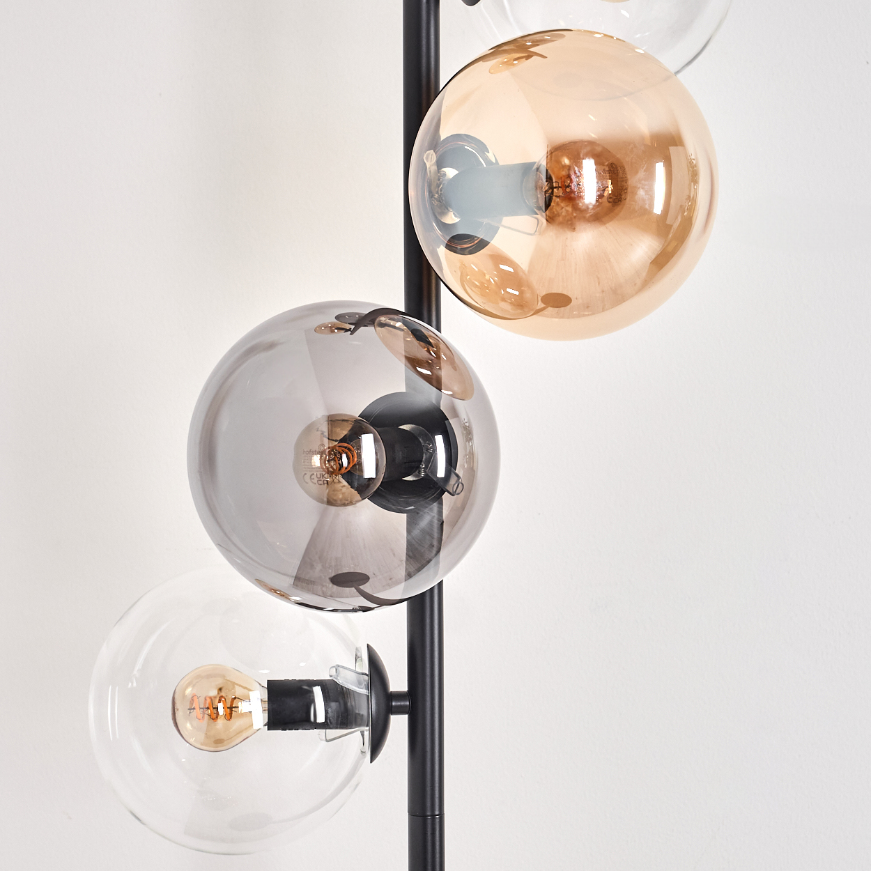 Nahaufnahme einer Stehlampe mit bernsteinfarbenen und silbernen Glaskugeln. Die Glühbirnen sind sichtbar.