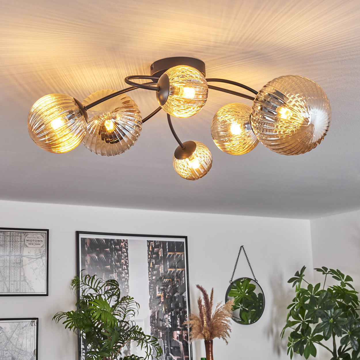 Deckenlampe mit sechs bernsteinfarbenen Glaskugeln an gebogenen schwarzen Armen. Innenraum mit Dekor.