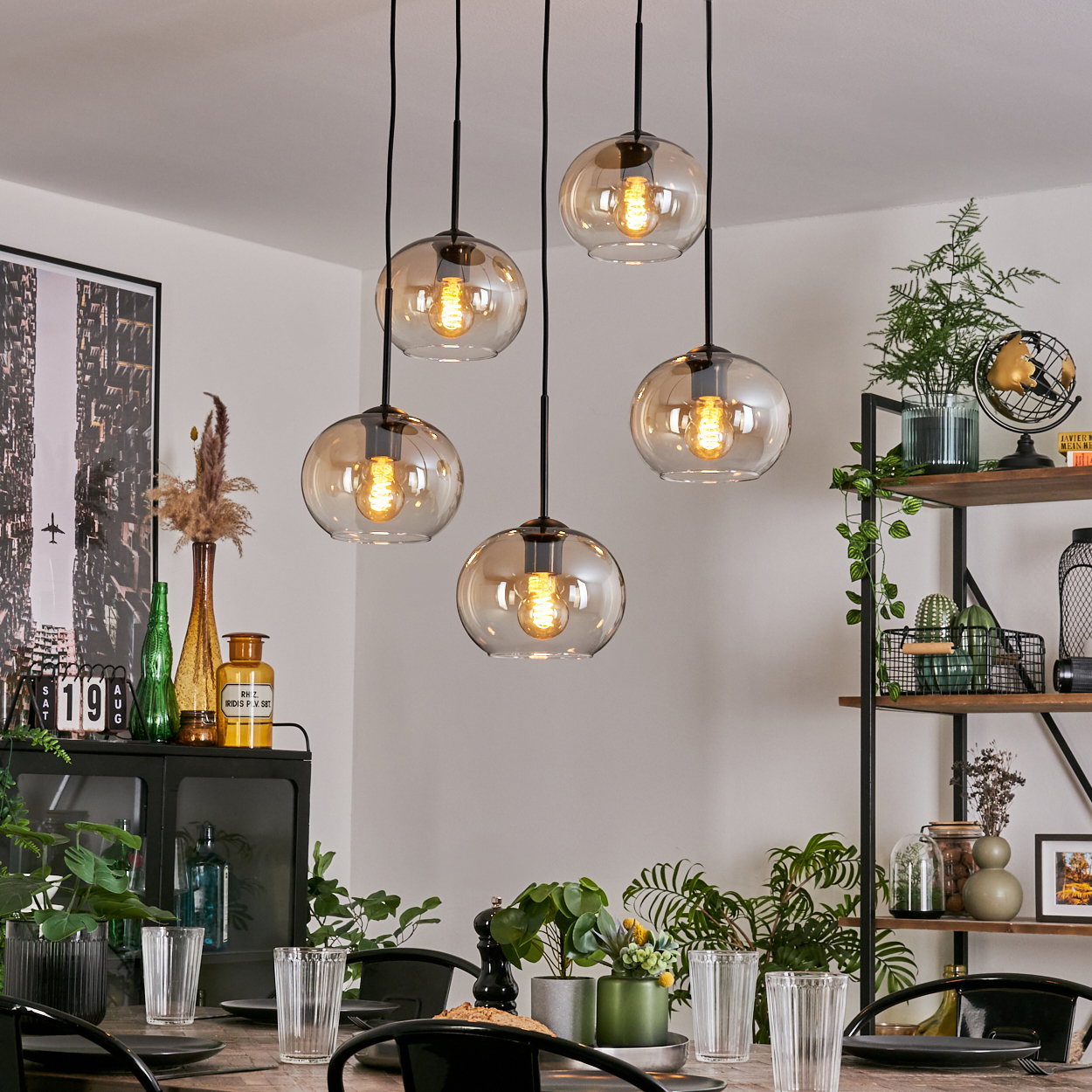 Esszimmer mit hängenden bernsteinfarbenen Glaskugelleuchten, Tisch mit Essen und Dekoration.