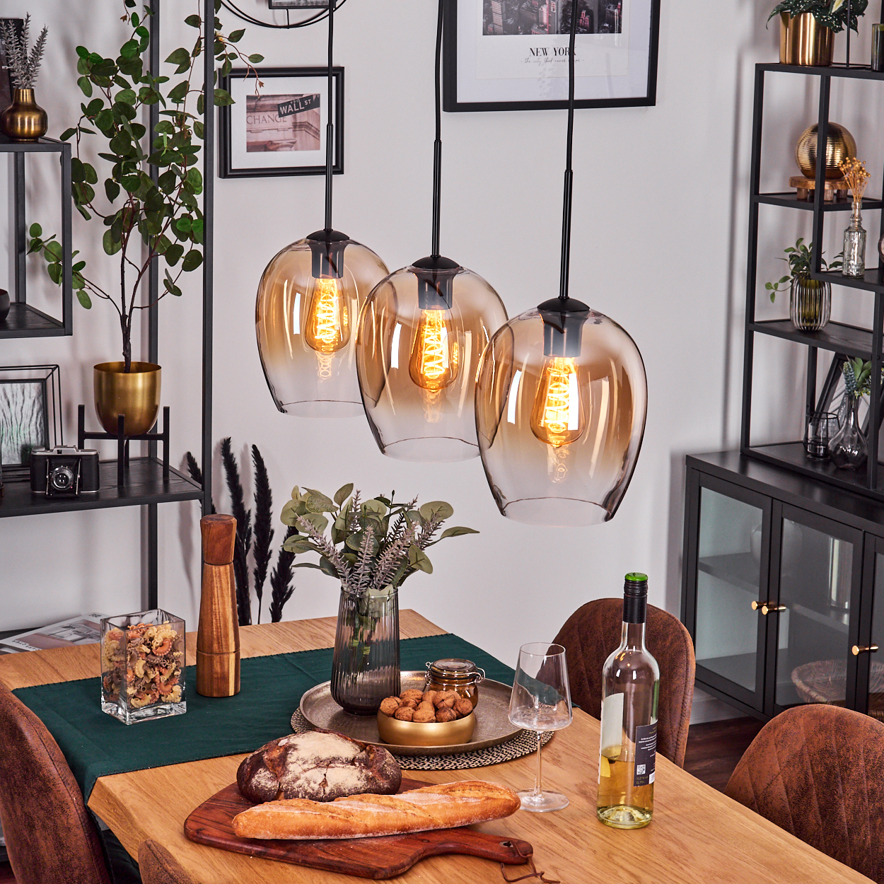Esszimmer mit hängenden bernsteinfarbenen Glaskugelleuchten, Essen und Dekoration auf dem Tisch.