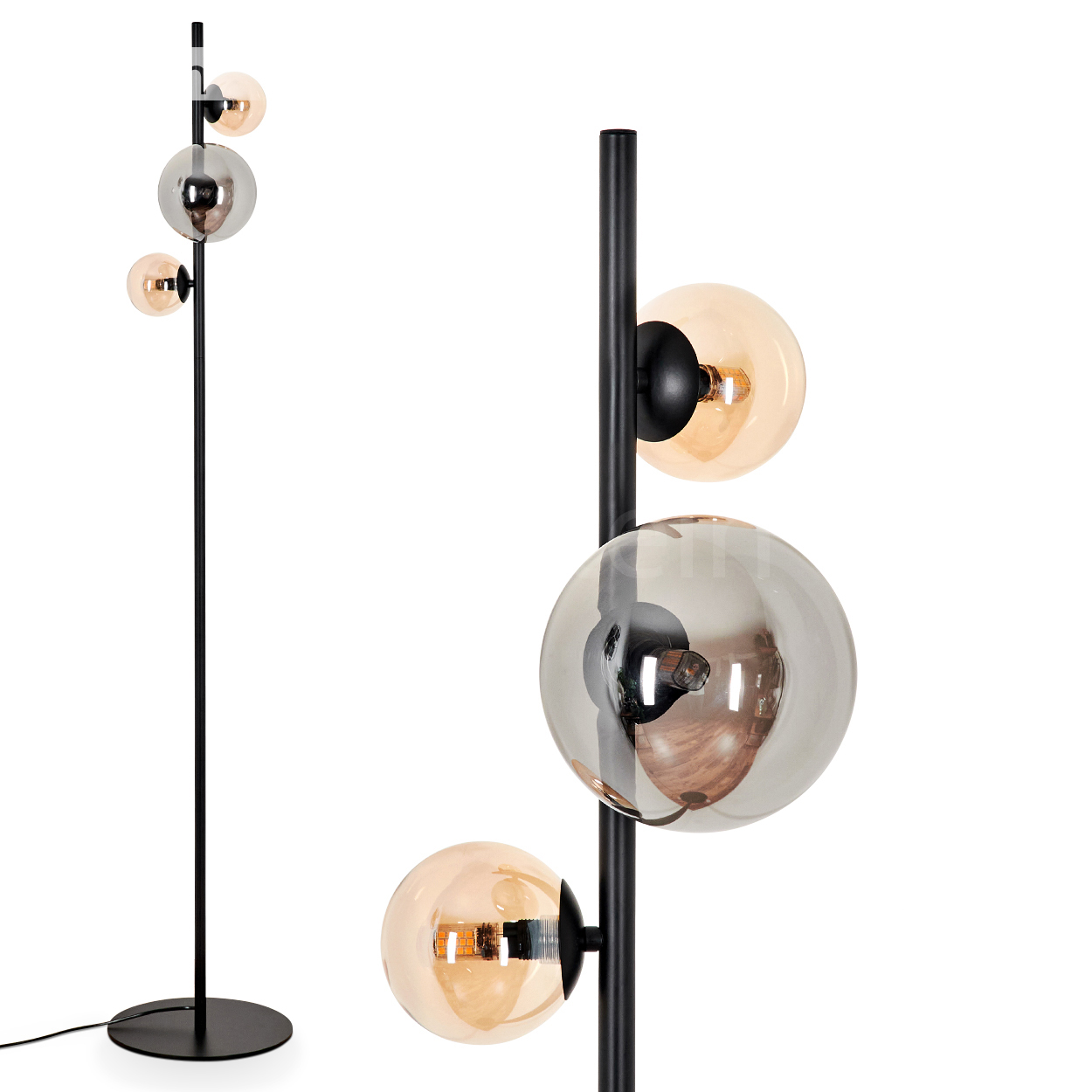 Eine schwarze Stehlampe mit drei Glaskugeln. Zwei bernsteinfarbene und eine silberne, auf weißem Hintergrund.