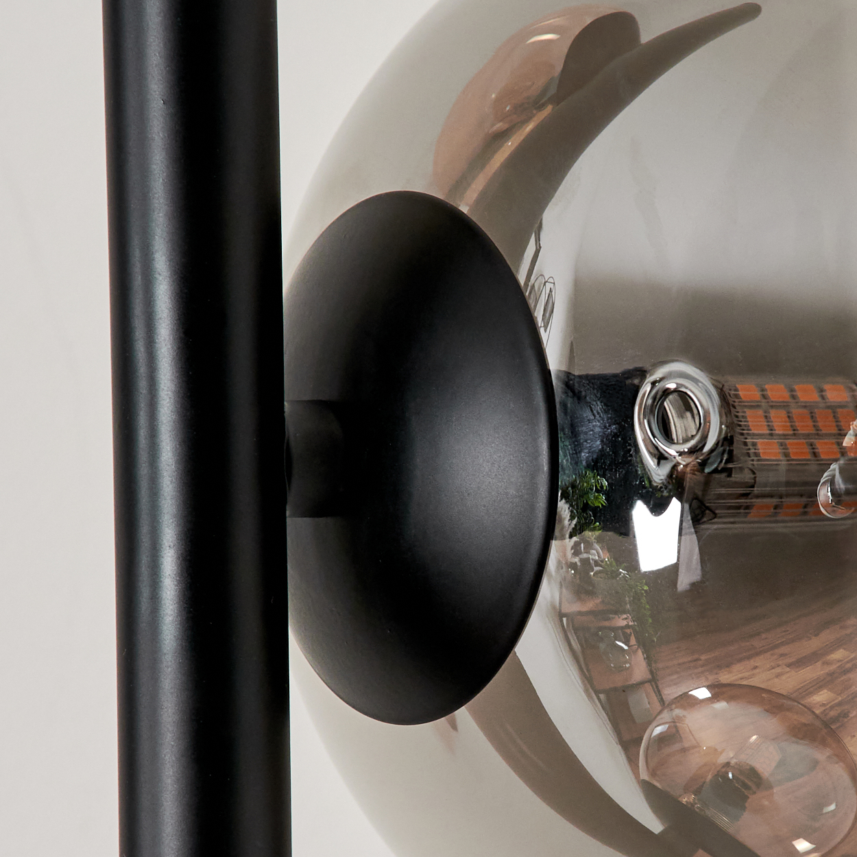 Nahaufnahme der Stehlampe mit bernsteinfarbenem Globus, schwarzem Stiel. Details der Lampe und Lichtquelle.