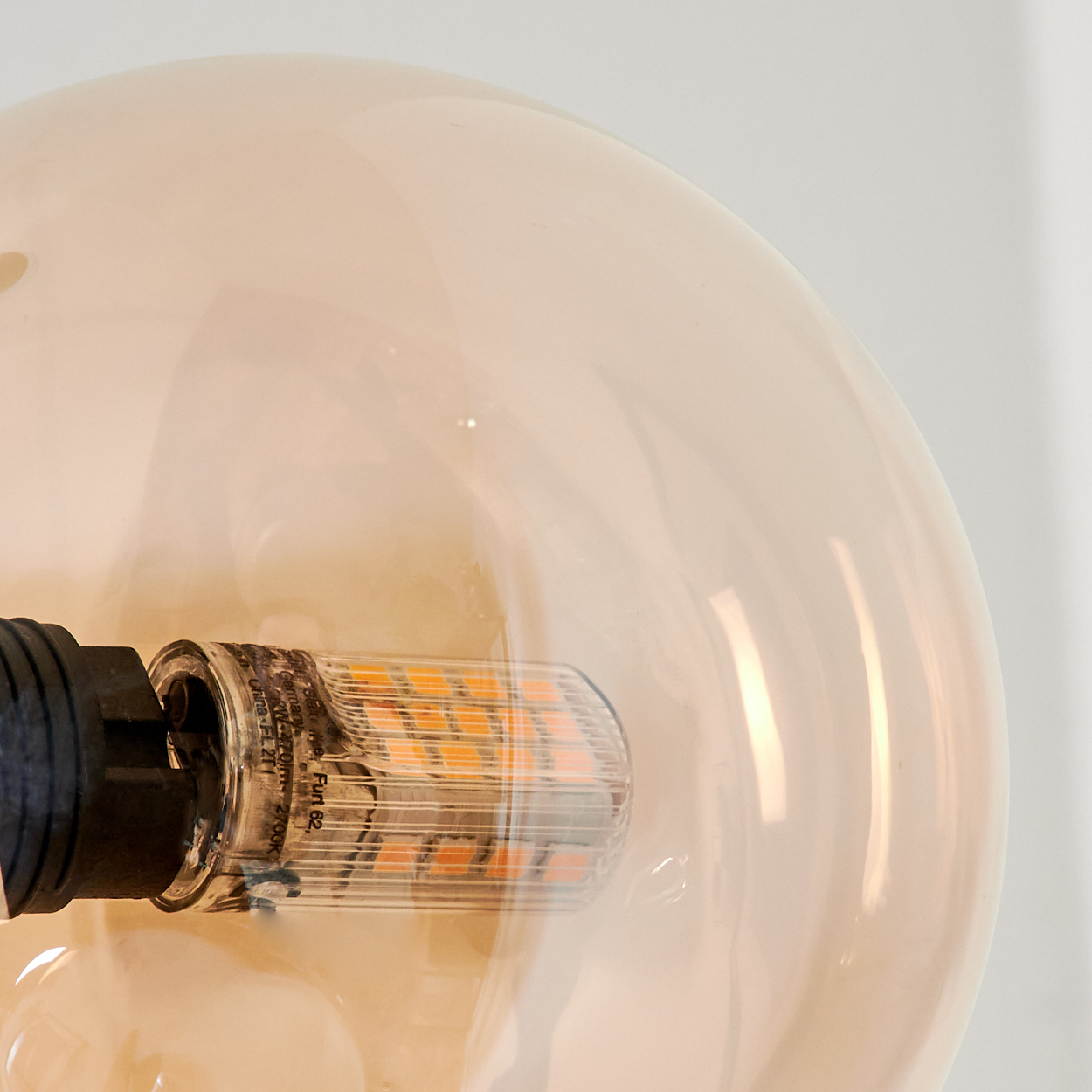 Nahaufnahme einer Glühbirne mit gelbem LED-Licht im Inneren, mit weißem Hintergrund.