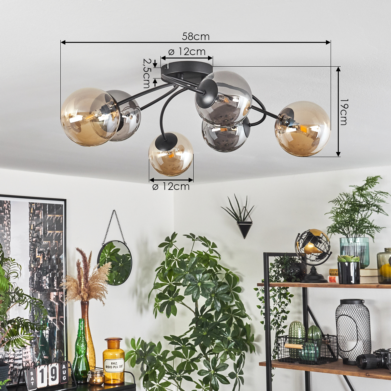 Deckenlampe mit 6 kugelförmigen Lichtern. Abmessungen sind angegeben. Raum mit Pflanzen und Dekorationen im Hintergrund.