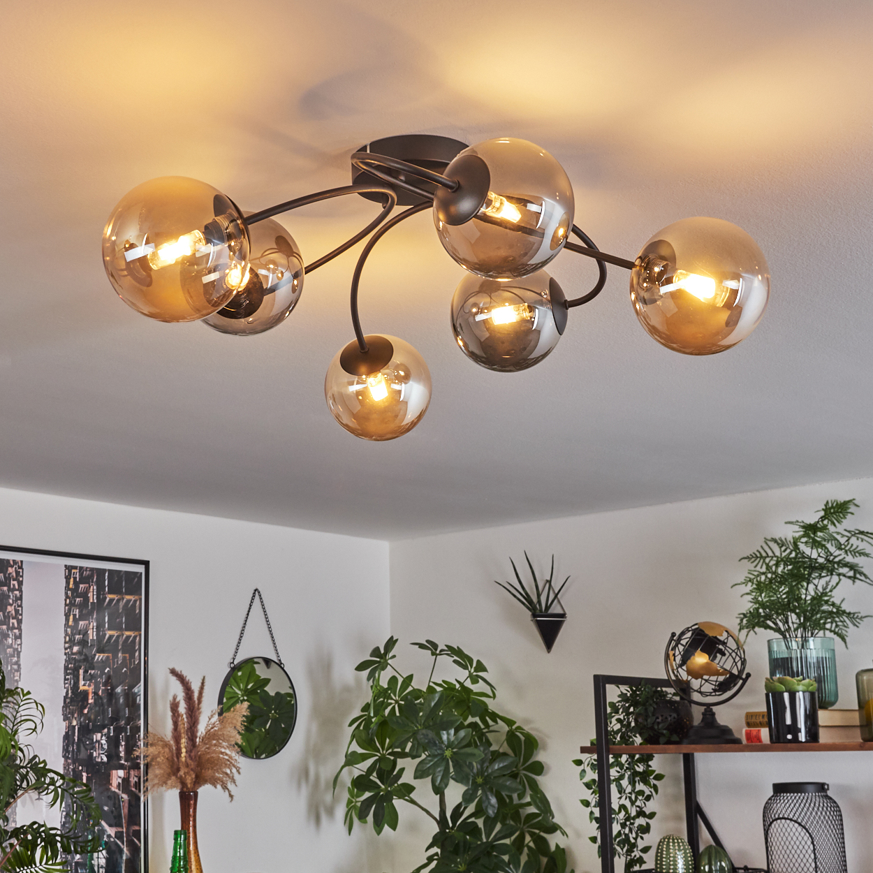 Deckenlampe mit sechs kugelförmigen Lichtern in einem Raum. Der Hintergrund umfasst Pflanzen, Spiegel und Dekorationen.