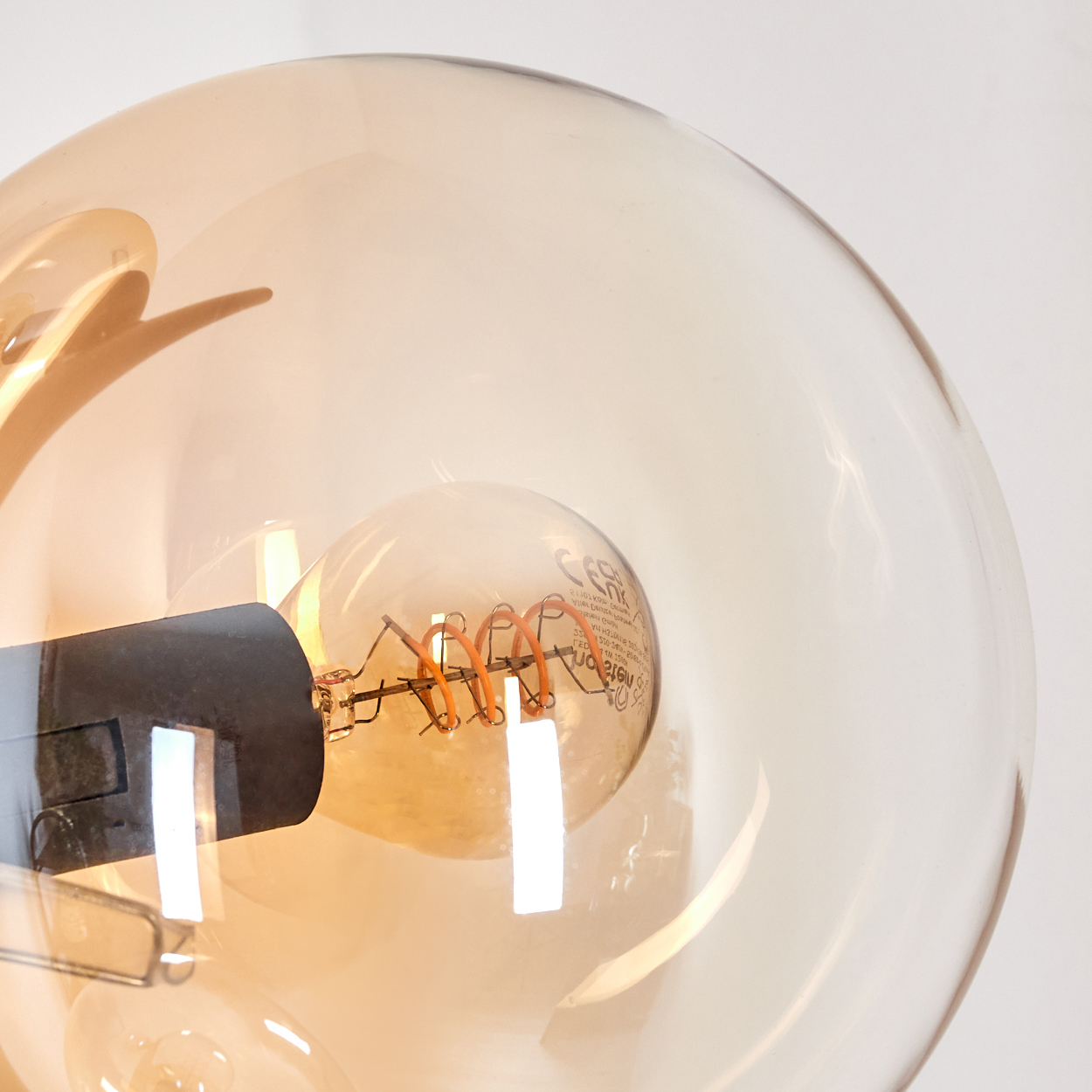 Nahaufnahme einer bernsteinfarbenen Glühbirne mit Spiralfaden in einem Glaskolben. Das Glas ist klar.