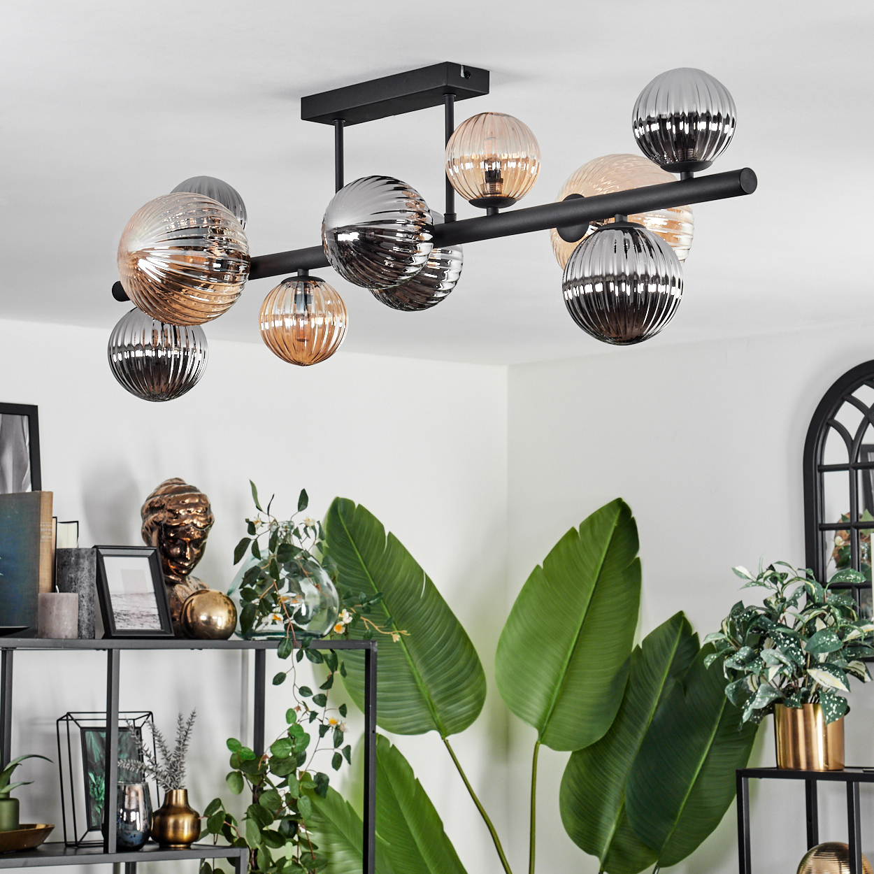 Deckenlampe mit mehreren Glaskugel-Lampen. Raum hat Pflanzen und Dekorationsartikel auf Regalen.