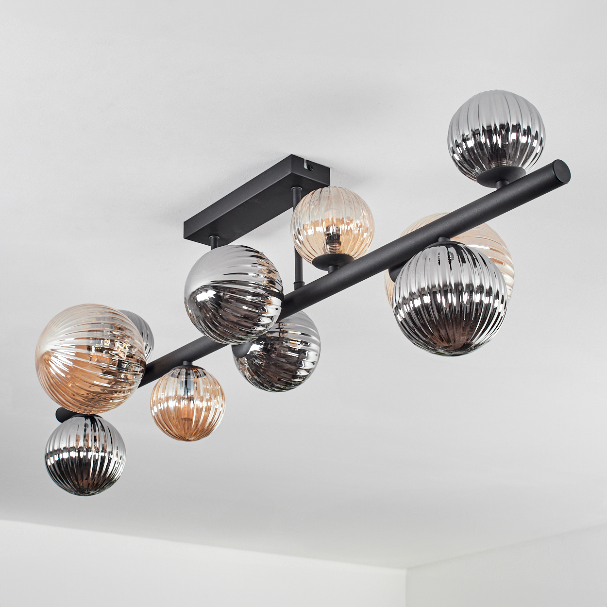 Deckenlampe mit mehreren Glaskugellampen. Die Lampen befinden sich auf einem schwarzen horizontalen Balken.