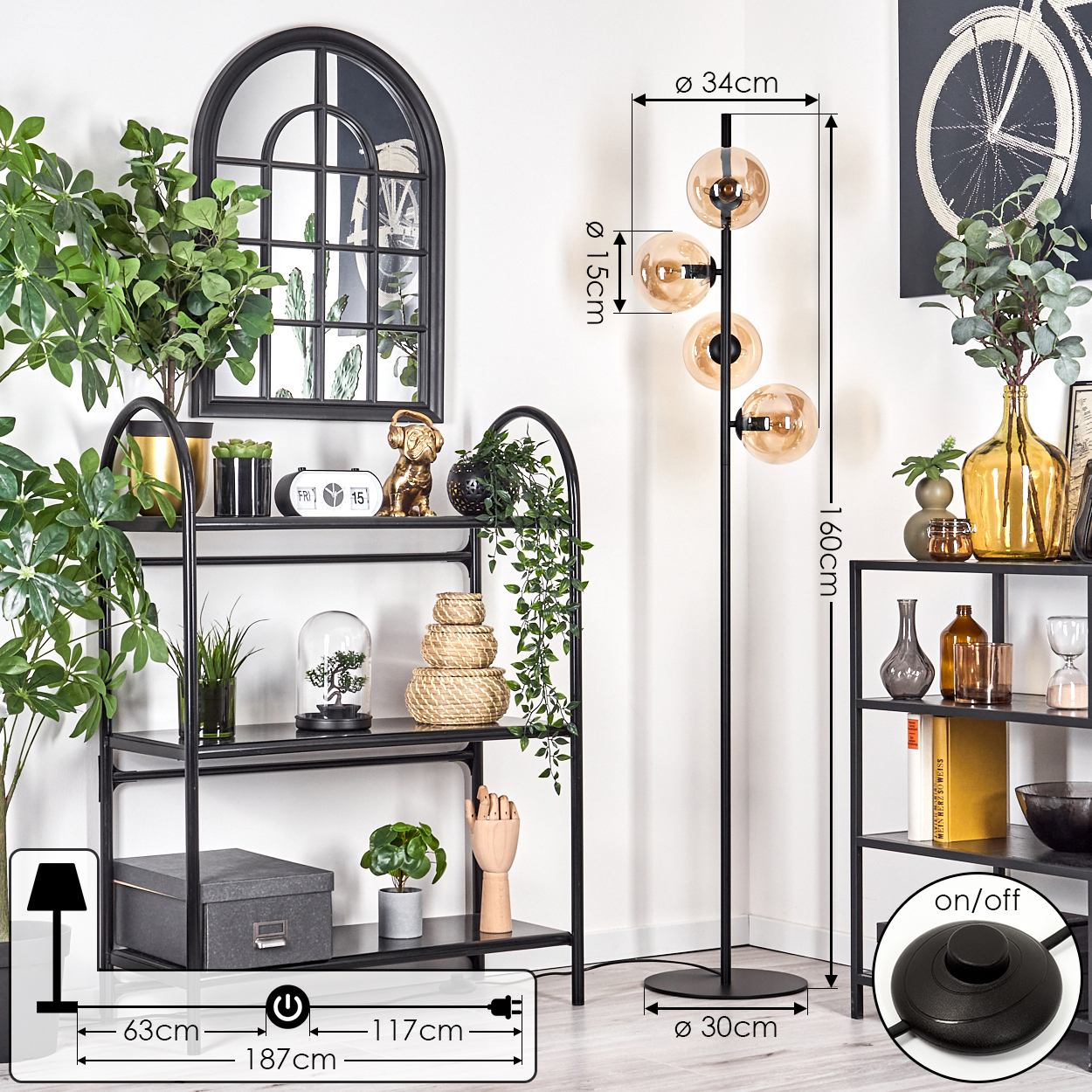 Schwarze Stehlampe mit bernsteinfarbenen Glaskugeln, schwarzem Fuß und Fußschalter. Regale im Hintergrund.