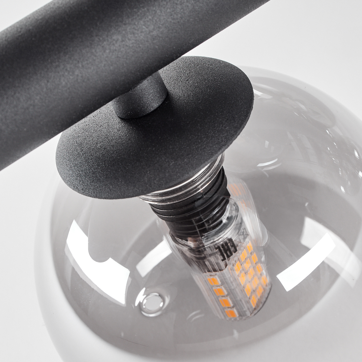 Nahaufnahme einer Lampenfassung mit transparentem Glaskolben und sichtbarem LED-Licht.
