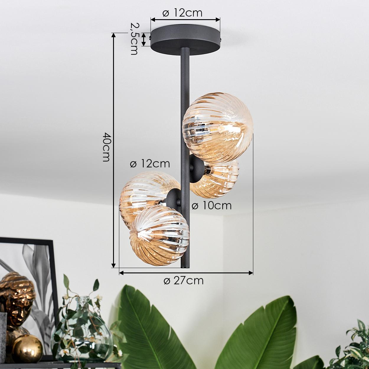 Deckenlampe mit bernsteinfarbenen Glaskugeln. Schwarzer Rahmen. Maße sind angegeben. Weiße Decke mit Pflanze.