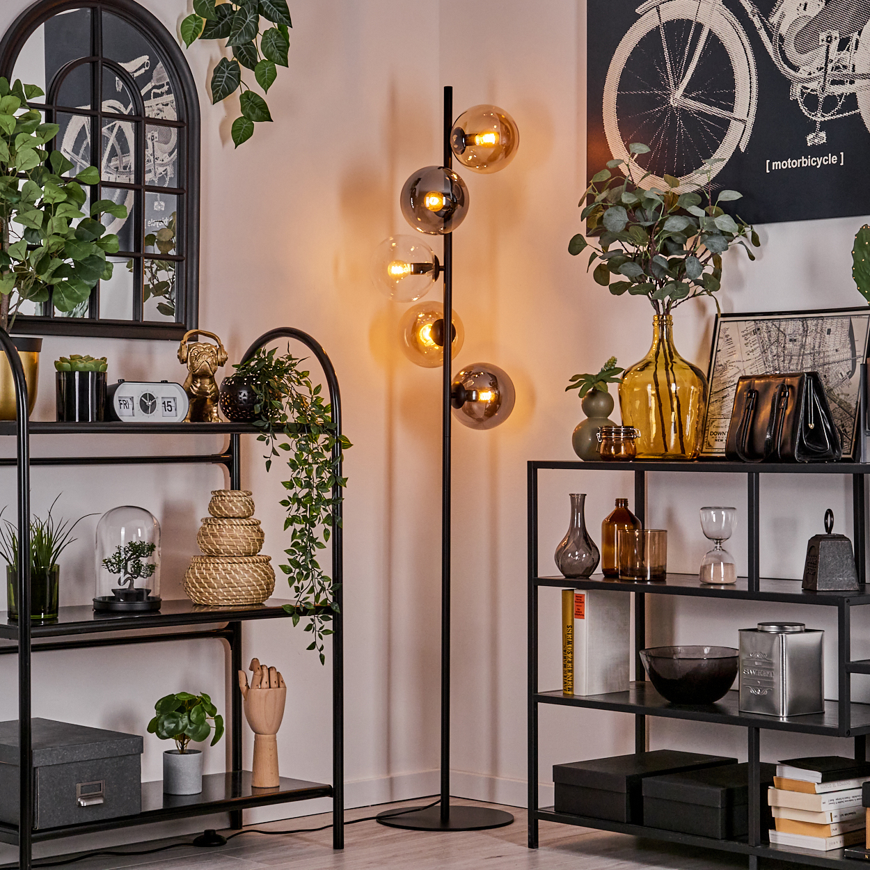 Ein Zimmer mit Stehlampe, Regalen und Dekoration. Die Lampe hat mehrere Glaskugeln.