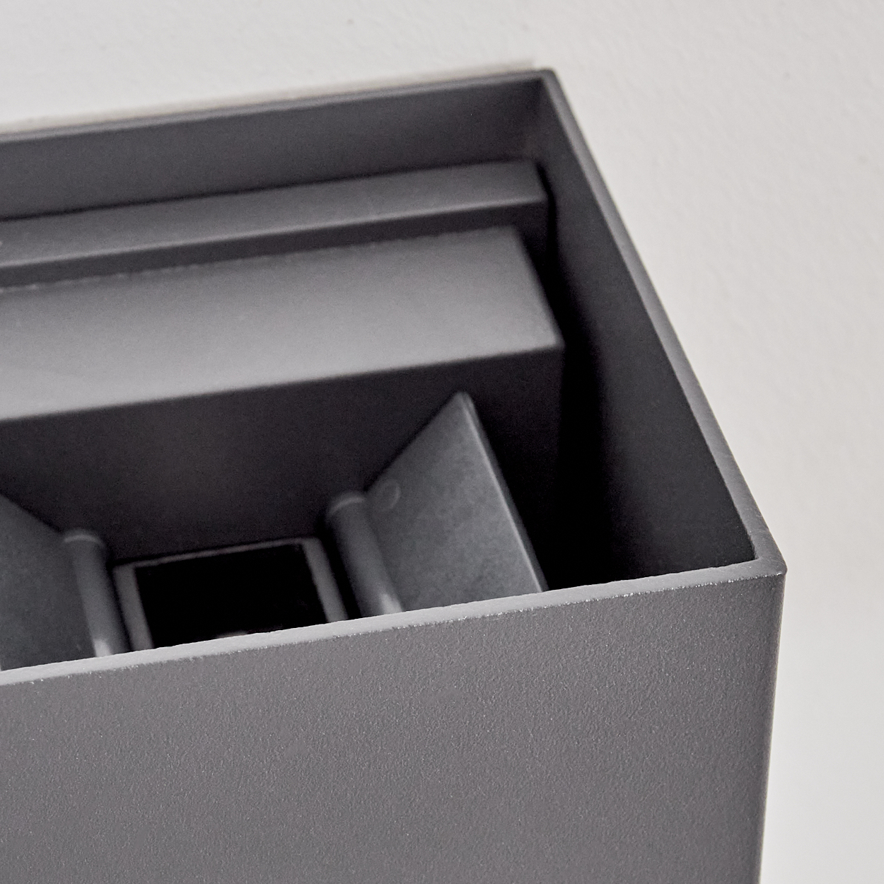 Graue rechteckige Box, möglicherweise eine Leuchtenkomponente, mit sichtbaren Innenstrukturen.