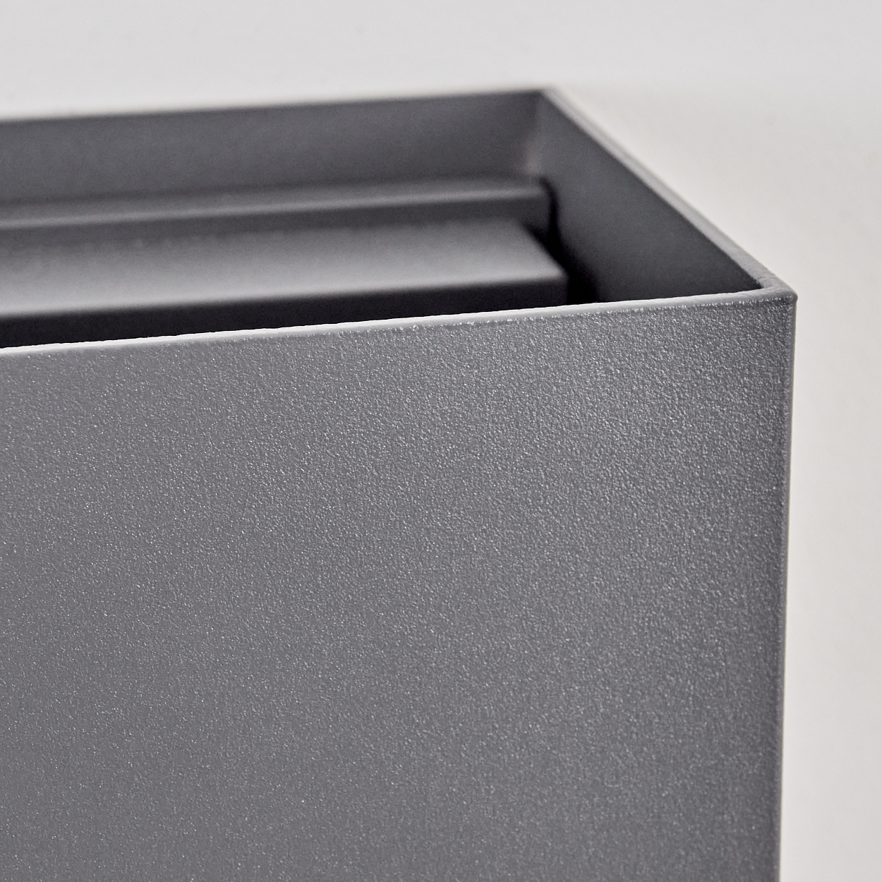Nahaufnahme einer grauen rechteckigen Box, die eine strukturierte Oberfläche und Innenstrukturen zeigt.