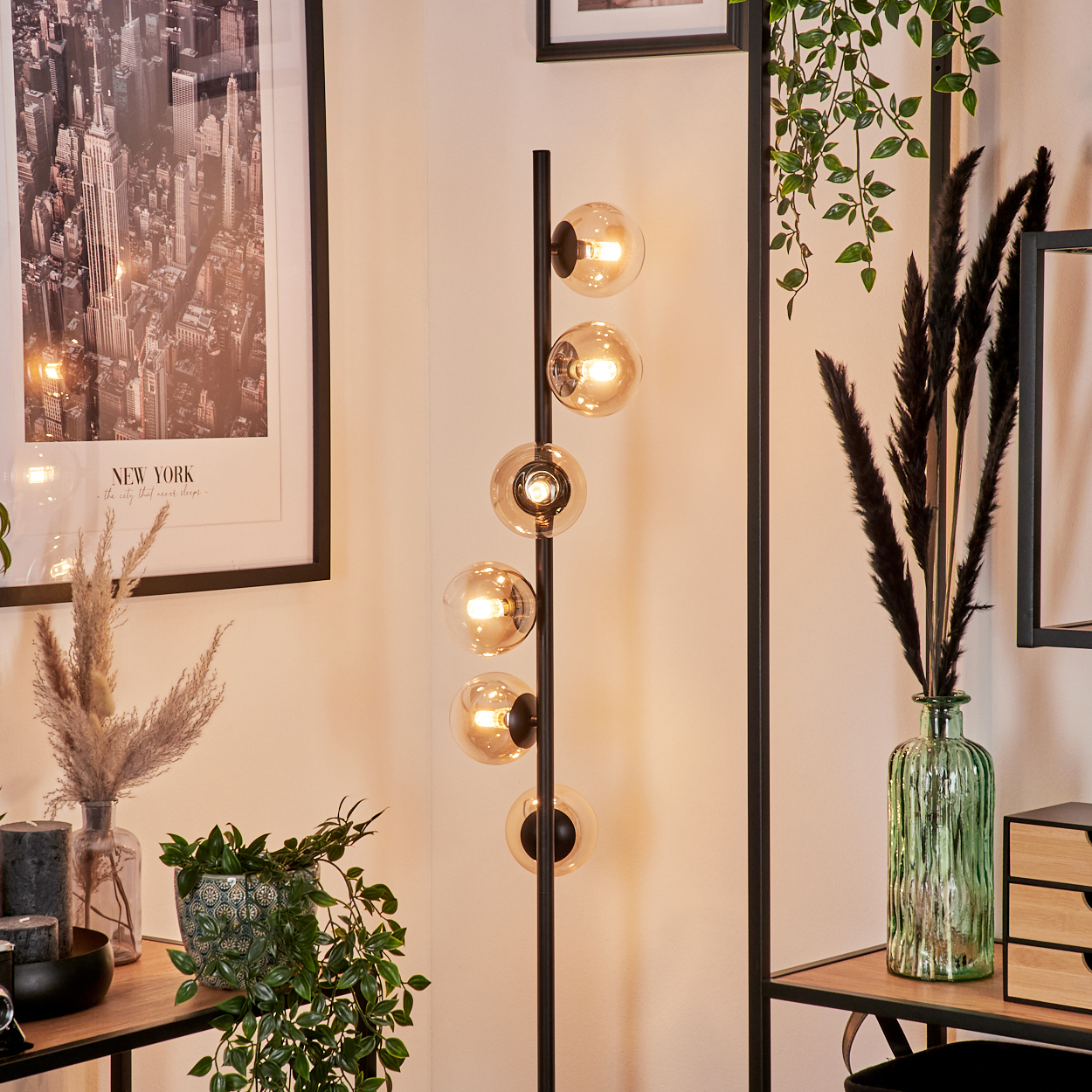 Moderne Stehlampe mit bernsteinfarbenen Kugeln. Inneneinrichtung mit Pflanzen und Dekoration.
