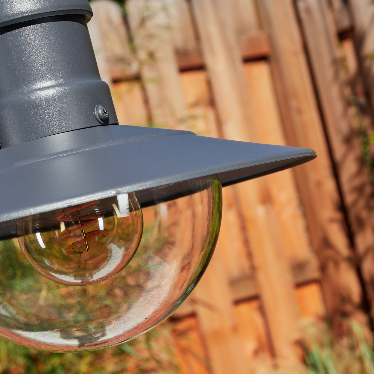 Nahaufnahme einer grauen Lampe mit durchsichtigem Glaskugel und Glühbirne.