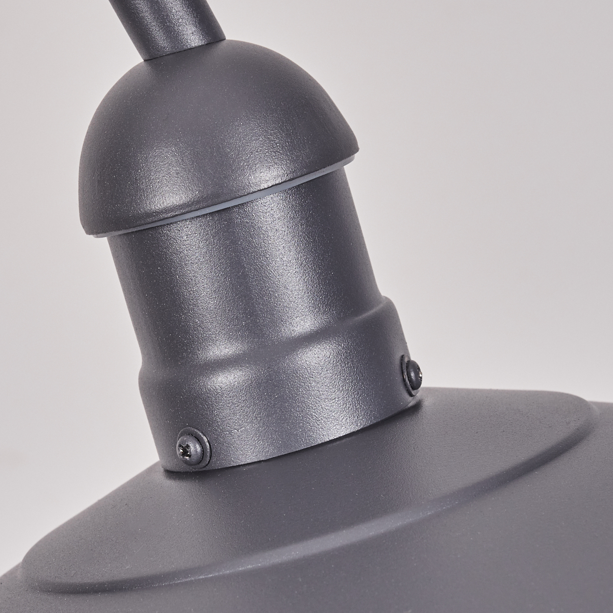 Nahaufnahme einer grauen Lampe mit gewölbter Form und sichtbaren Schrauben.